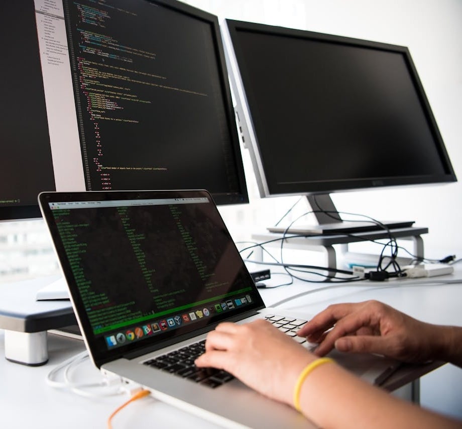 Homme sur un triple écran en train de coder